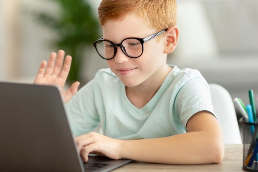 kid-waving-at-computer-during-virtual-hybrid-class-at-home-900x600