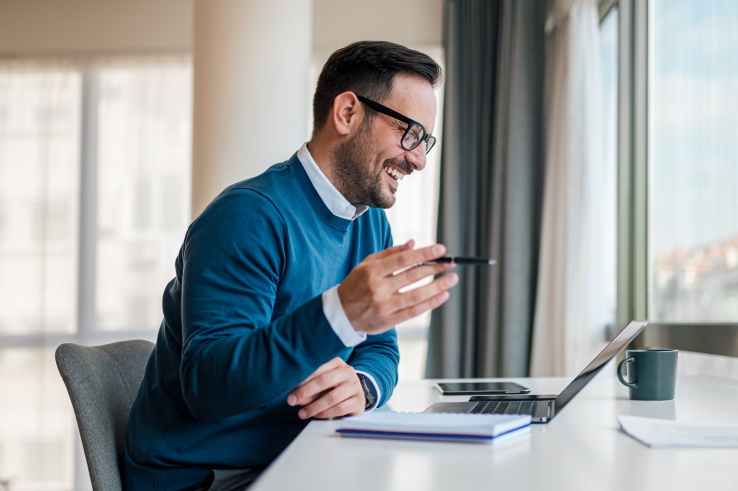 professional man smiling and gesturing at laptop while participating in company training at home